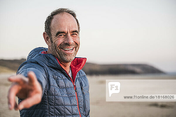 Happy mature man gesturing peace sign at beach