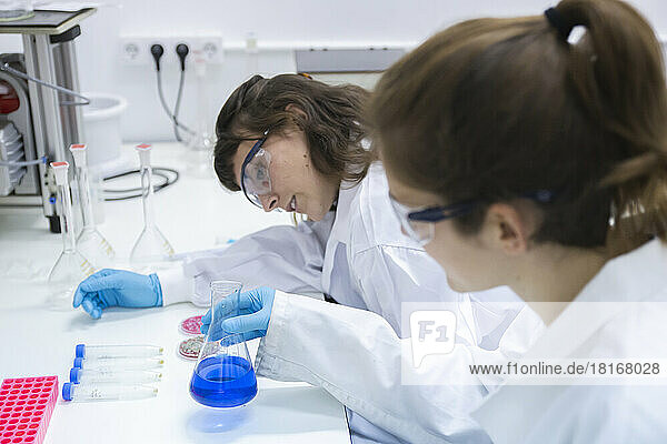 Scientists examining blue chemical in flask at laboratory