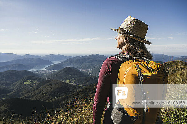 Woman standing with backpack in front of mountains at vacation