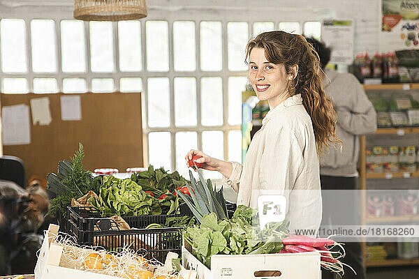 Smiling woman buying vegetables from greengrocer shop
