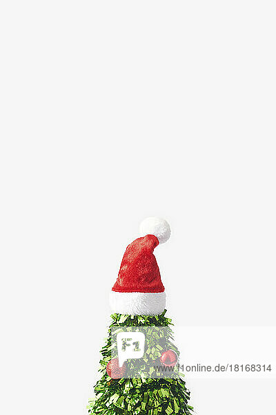 Christmas tree made of green confetti with santa hat on top against white background