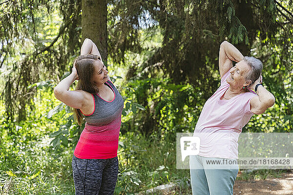 Happy fitness instructor teaching exercise to senior woman at park