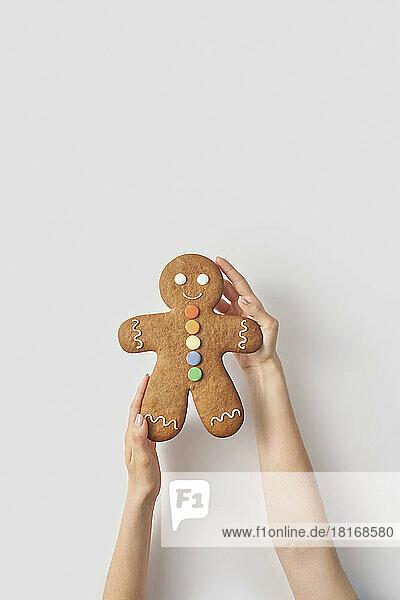 Woman holding gingerbread man cookie on white background