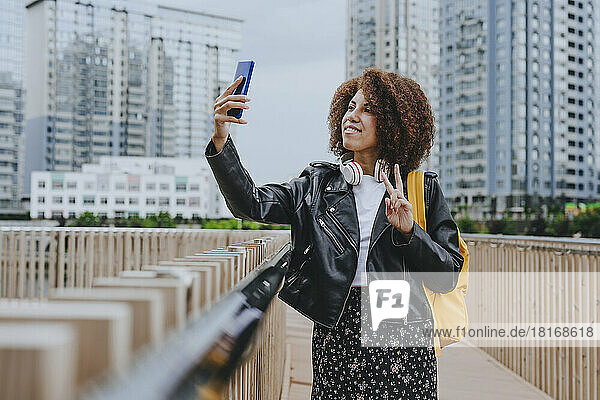 Young woman taking selfie through mobile phone standing on bridge