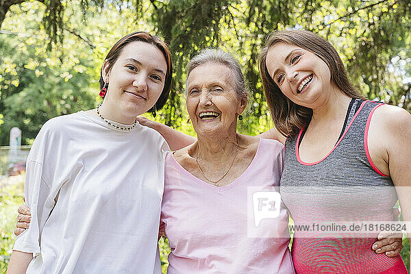 Cheerful senior woman with daughter and granddaughter standing at park
