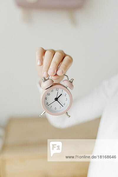 Hand of girl holding alarm clock