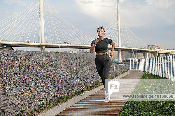Smiling woman jogging on footpath