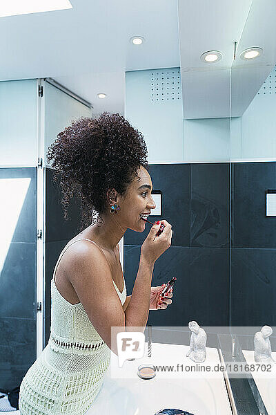 Frau trägt zu Hause im Badezimmer Lippenstift auf