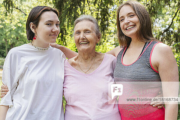 Happy senior woman with daughter and granddaughter standing at park