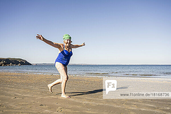 Sorglose ältere Frau  die an einem sonnigen Tag Spaß am Strand hat