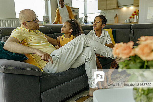 Vater mit Kindern sitzt zu Hause auf dem Sofa im Wohnzimmer