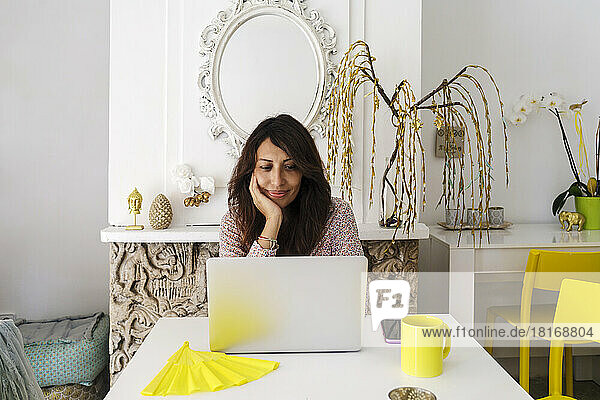 Smiling freelancer working on laptop at table