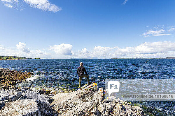 Mann steht auf einem Felsen am Loch Ailort See
