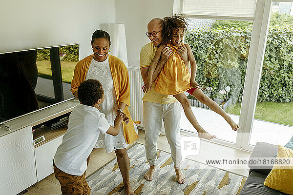 Glückliche Eltern mit Kindern  die zu Hause im Wohnzimmer tanzen