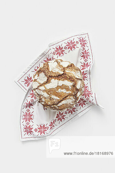 Panettone cake with crunchy crust on table napkin against white background