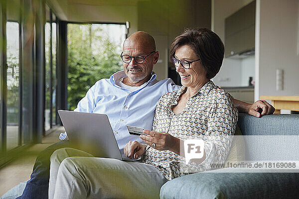 Happy couple making payment through credit card on laptop at home