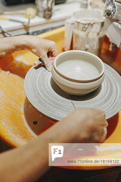 Hands of potter working on pottery wheel at ceramics workshop