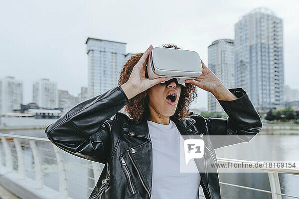 Shocked woman using VR glasses in city