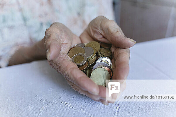 Coins in hands of senior woman at home