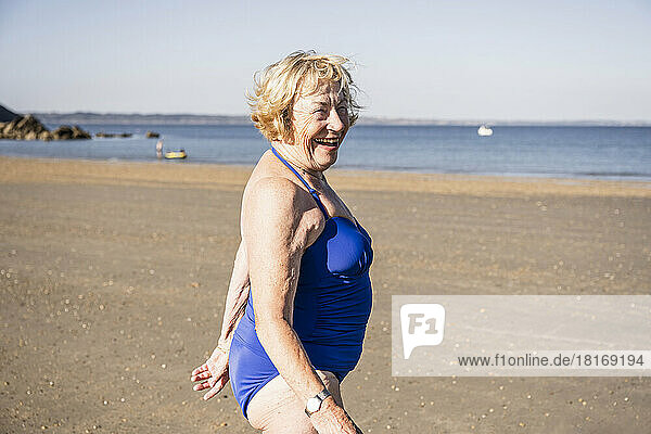 Glückliche ältere Frau  die an einem sonnigen Tag am Strand genießt