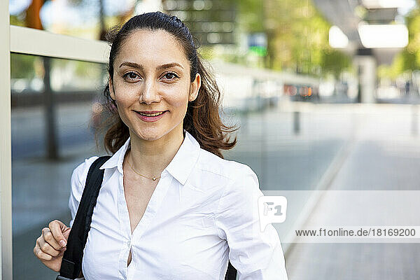 Happy businesswoman standing at footpath