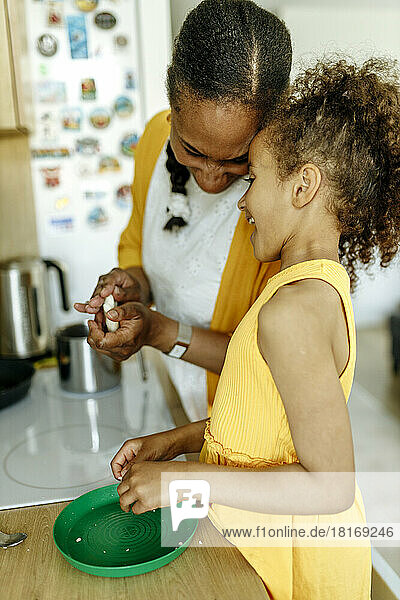 Glückliche Frau mit Tochter bereitet Essen in der Küche zu
