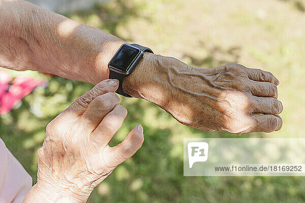 Hands of senior woman wearing smart watch on sunny day
