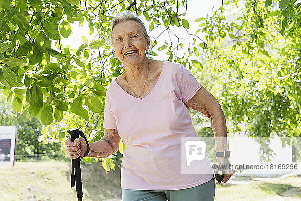 Happy senior woman exercising with walking pole at park