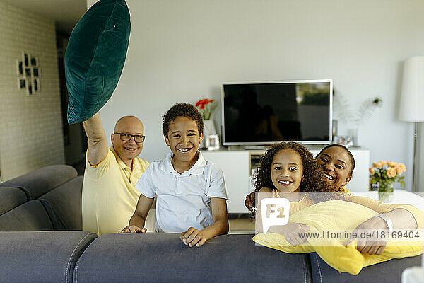 Lächelndes Mädchen und Junge mit Eltern auf dem Sofa zu Hause