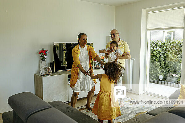 Happy children with parents dancing in living room at home