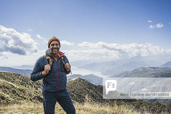 Mature man with knit hat standing in front of mountains
