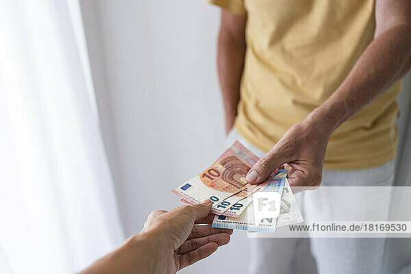 Mature man paying with banknotes at home