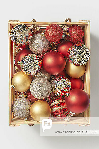 Wooden box with shiny christmas baubles against white background