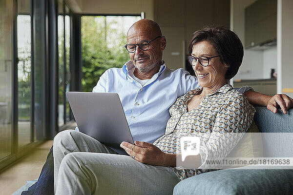 Happy senior woman with man using laptop at home