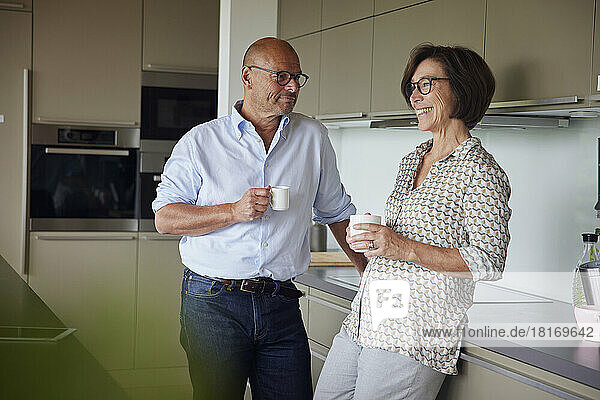 Glückliche Frau und Mann stehen zu Hause in der Küche
