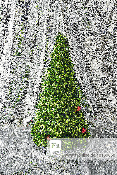 Geschmückter Konfetti-Weihnachtsbaum vor glänzenden silbernen Pailletten