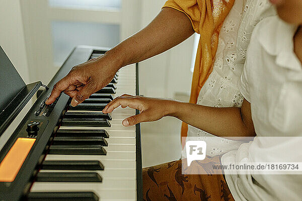 Hand of woman teaching son to play piano