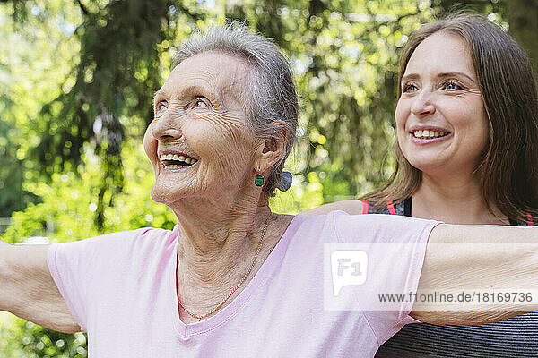 Happy senior woman with fitness instructor exercising at park