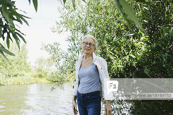 Senior woman with eyeglasses standing by plants