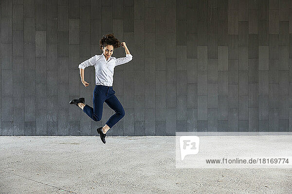 Carefree woman jumping in front of wall