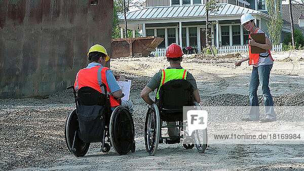 Construction engineers discussing site issues  men in wheelchairs with spinal cord injuries; Plymouth  Massachusetts  United States of America