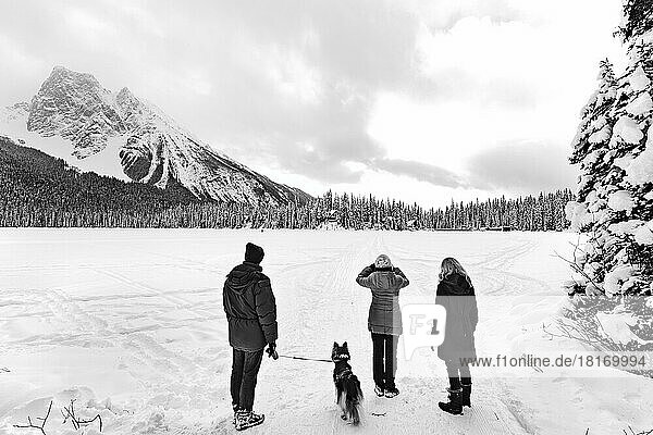 Tourists hiking across a frozen Emerald Lake with the Rocky Mountains in the background during winter in Yoho National Park; British Columbia  Canada