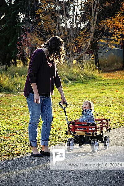 Eine Mutter zieht ihr Baby mit Down-Syndrom in einem Wagen in einem Stadtpark während der Herbstsaison; St  Albert  Alberta  Kanada