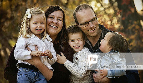 Porträt einer jungen Familie mit drei Kindern  die jüngste Tochter mit Down-Syndrom  in einem Stadtpark während der Herbstsaison; St. Albert  Alberta  Kanada