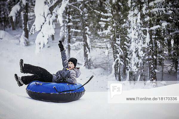 Young boy tubing down a ski hill; Fairmont Hot Springs  British Columbia  Canada
