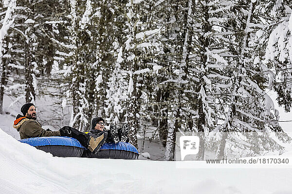 Vater und Sohn beim Tubing auf einem Skihügel; Fairmont Hot Springs  British Columbia  Kanada