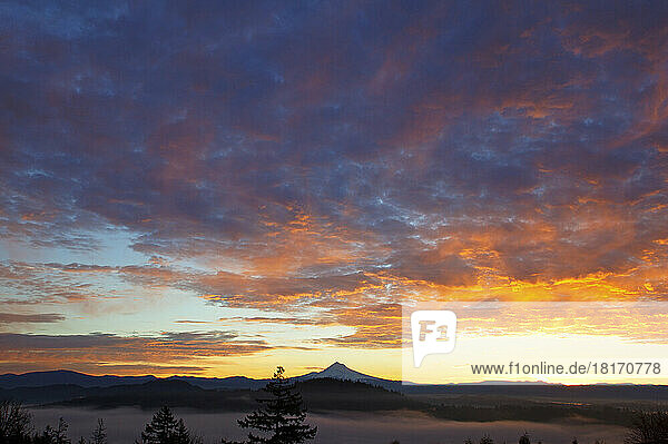 Dramatische glühende Wolken über einem silhouettierten Mount Hood bei Sonnenaufgang; Oregon  Vereinigte Staaten von Amerika
