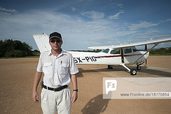 Ein Pilot steht neben seinem Flugzeug auf einer Landebahn; Uganda