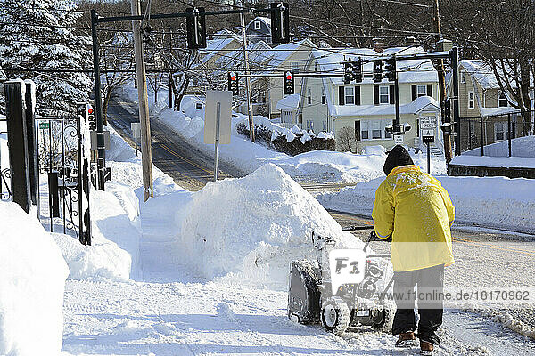 A person with a snow blower cleaning up after a record storm in the Boston area.; Arlington  Massachusetts.