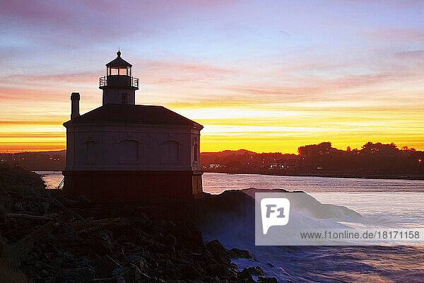 Coquille River Light on the rugged and rocky Oregon coast with golden sunrise light over the horizon; Bandon  Oregon  United States of America